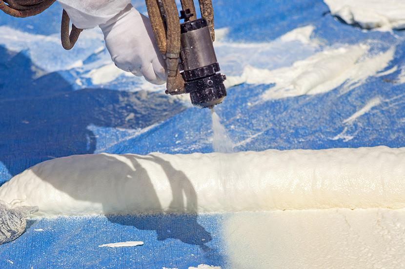 person spraying polyurethane foam insulation on a roof